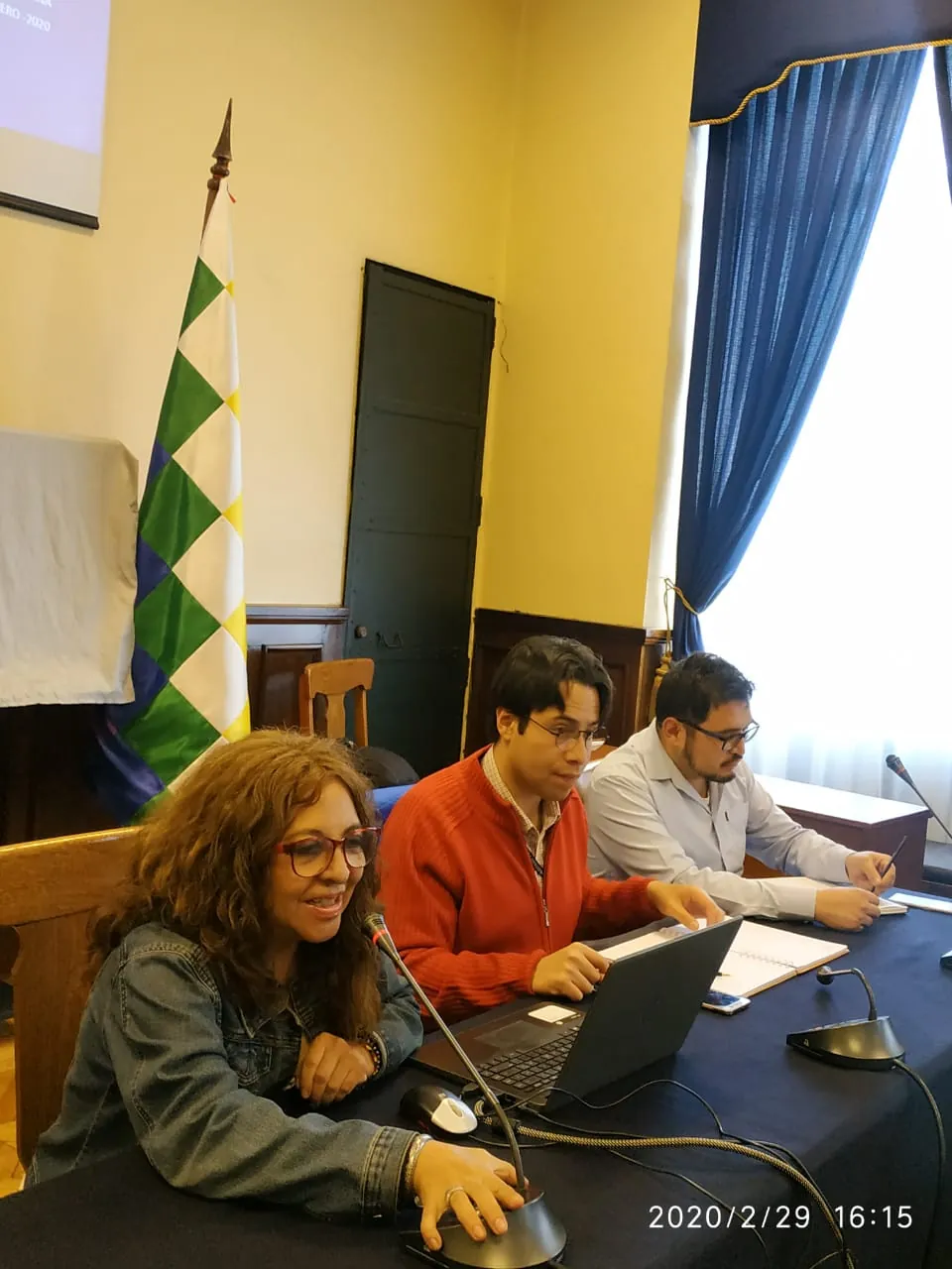 Participantes en una sala con la bandera de Bolivia al fondo